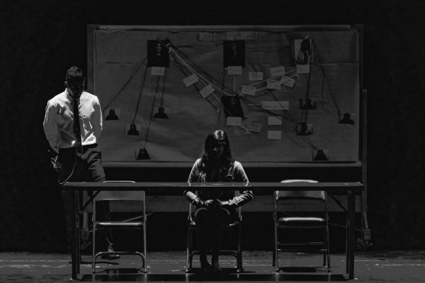 Black and white scene depicting a tense interrogation with suspect and investigator.