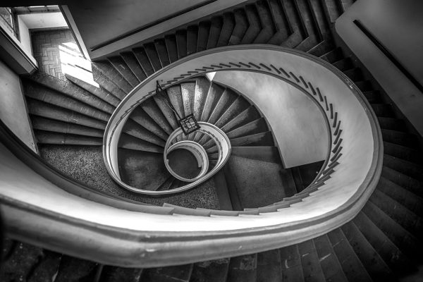 Captivating black and white photo of a spiral staircase viewed from above, showcasing architectural beauty.