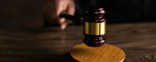 A gavel striking a sound block, symbolizing justice and legal authority in a courtroom setting.